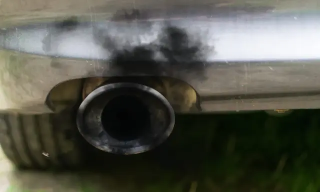 Zanieczyszczony układ wydechowy samochodu, czarny dym wydobywa się z rury. Czas na czyszczenie DPF.