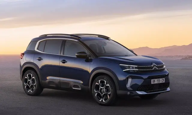 Ciemnoniebieski, kompaktowy SUV Citroën C5 Aircross na tle zachodzącego słońca nad morzem.