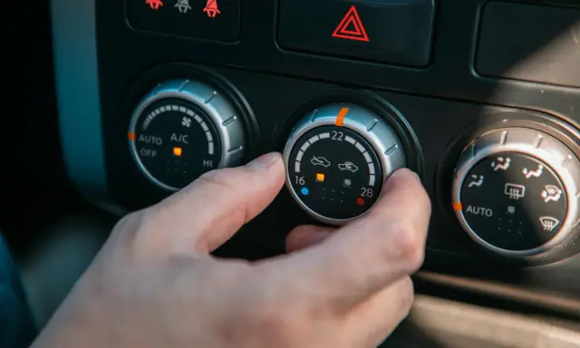 Dłoń kręci pokrętłem klimatyzacji, próbując zdiagnozować objawy zepsutego termostatu.
