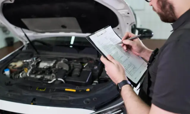 Mechanik sprawdza listę kontrolną przed przeglądem technicznym samochodu. Oplata za przeglad jest już ustalona.