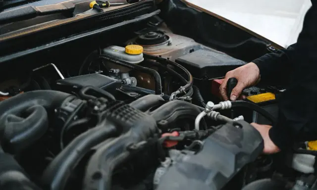 Mechanik pracuje przy silniku, sprawdzając, czy sucha miska olejowa jest szczelna.