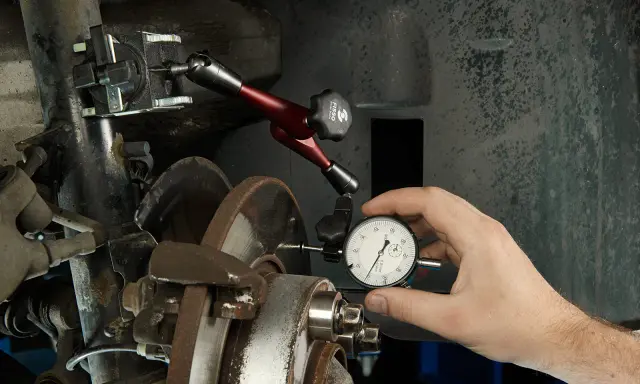 Mechanik mierzy bicie przy hamowaniu z dużej prędkości za pomocą czujnika zegarowego.