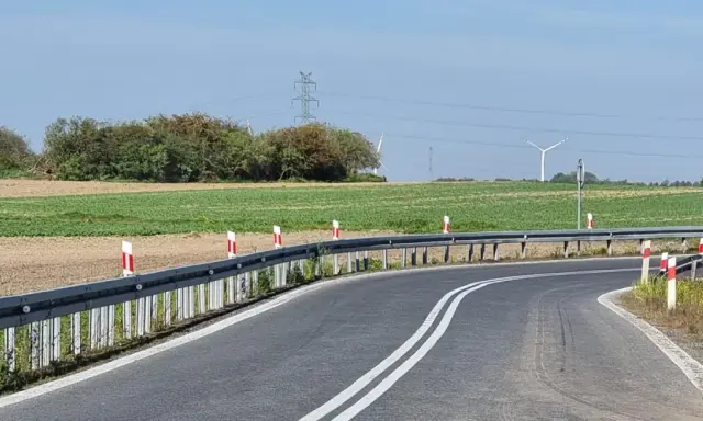 Oznaczenia na słupkach drogowych wzdłuż zakrętu drogi, prowadzącej przez pola i w pobliżu linii energetycznych.