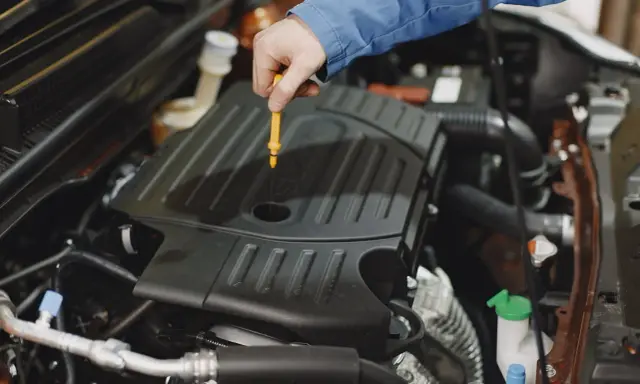 Mechanik sprawdza poziom oleju w silniku, aby wiedzieć, kiedy dolewać olej do silnika.