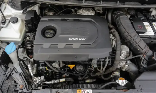 Silnik CRDi 1.6V w samochodzie. Widoczny czarny plastikowy dekiel silnika z napisem CRDi 16V, elementy układu dolotowego i chłodzenia.