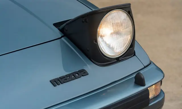 Mazda RX-7 z silnikiem Wankla. Charakterystyczny, wysuwany reflektor i logo marki na niebieskim lakierze.