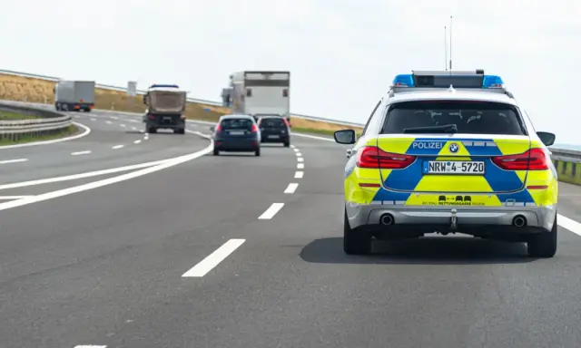 Niemiecka autostrada bez ograniczeń, gdzie policyjny radiowóz jedzie za innymi pojazdami.