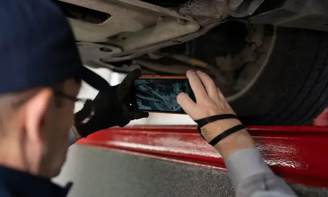 Mechanik robi zdjęcie podwozia auta, by sprawdzić numer VIN.