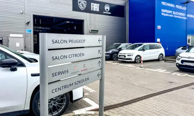 Znak kierunkowskazów w ASO wskazuje salon Peugeot, salon Citroën, serwis i centrum szkoleń.