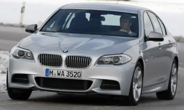 Srebrne BMW z kierowcą za kierownicą, gotowe do liftingu auta na zimowej drodze.