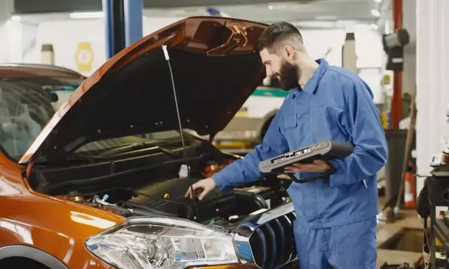 Mechanik z komputerem diagnostycznym sprawdza silnik. Zastanawiasz się, ile trwa wymiana oleju? To szybka usługa.