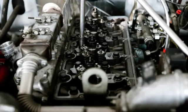 Mechanik bada silnik, szukając przyczyn spalania stukowego. Widoczne zawory i wtryskiwacze.