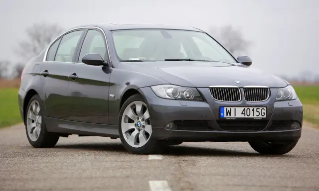 Szary sedan BMW e90 przedlift na drodze. Klasyczna linia nadwozia i charakterystyczne "nerki" na grillu.
