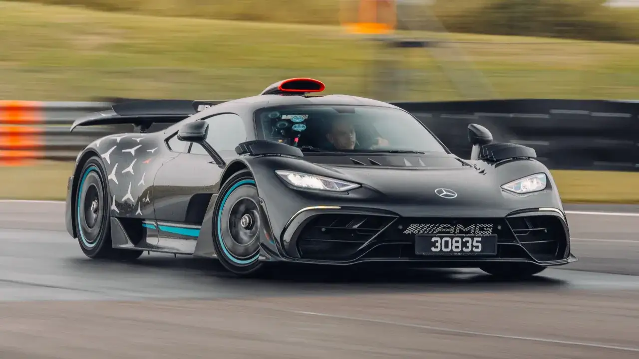 Czarny Mercedes-AMG Project One z czerwonym wlotem powietrza na dachu pędzi po torze wyścigowym.