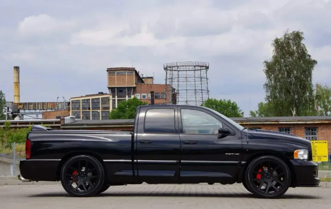 Czarny Dodge Ram 1500 SRT-10, potężny pickup, prezentuje swoje imponujące ramiona na tle postindustrialnego krajobrazu.
