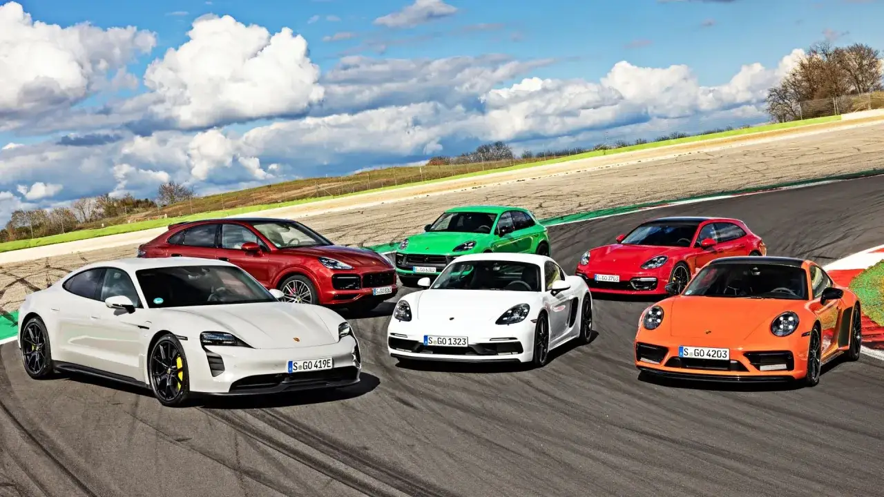 R&oacute;żne rodzaje Porsche: biały Taycan, czerwony Cayenne, zielony Macan, biały Cayman, czerwona Panamera i pomarańczowy 911 na torze wyścigowym.
