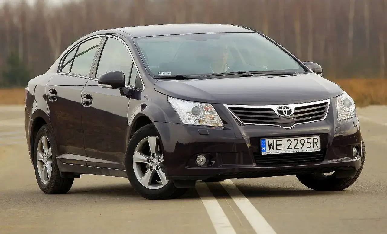 Ciemnofioletowa Toyota Avensis z polskimi tablicami WE 2295R jedzie po drodze.