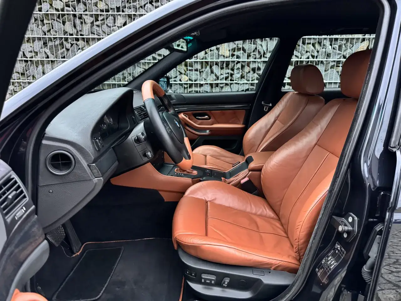 Wnętrze klasycznego BMW z brązową sk&oacute;rzaną tapicerką. Widok na fotele, deskę rozdzielczą i kierownicę. Te bmw modele stare zachwycają elegancją.